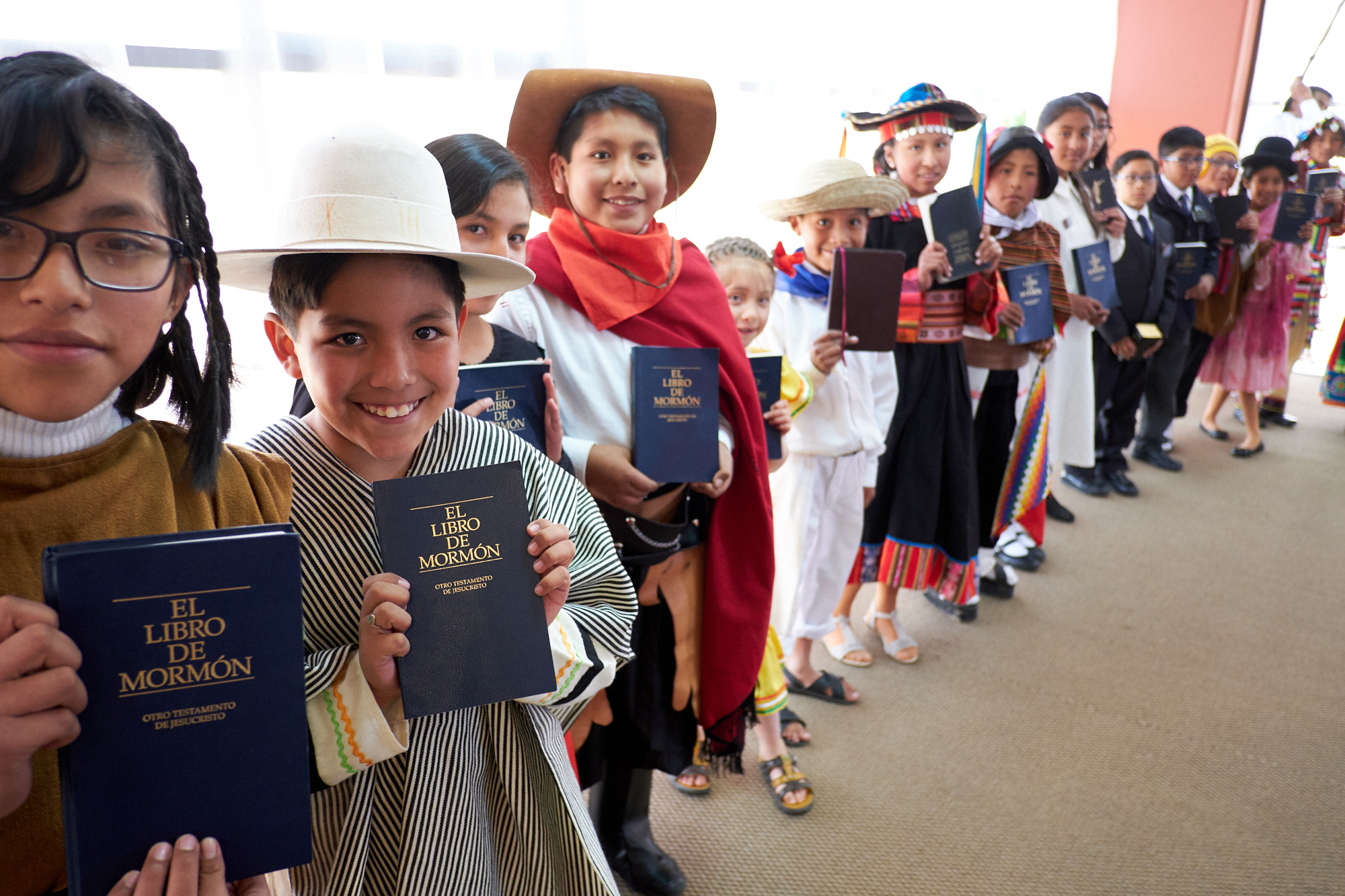 Latter-day Saint children line up in the Polideportivo Heroes de Octobre in El Alto, Bolivia, to show President Russell M. Nelson their copies of the Book of Mormon in Spanish.