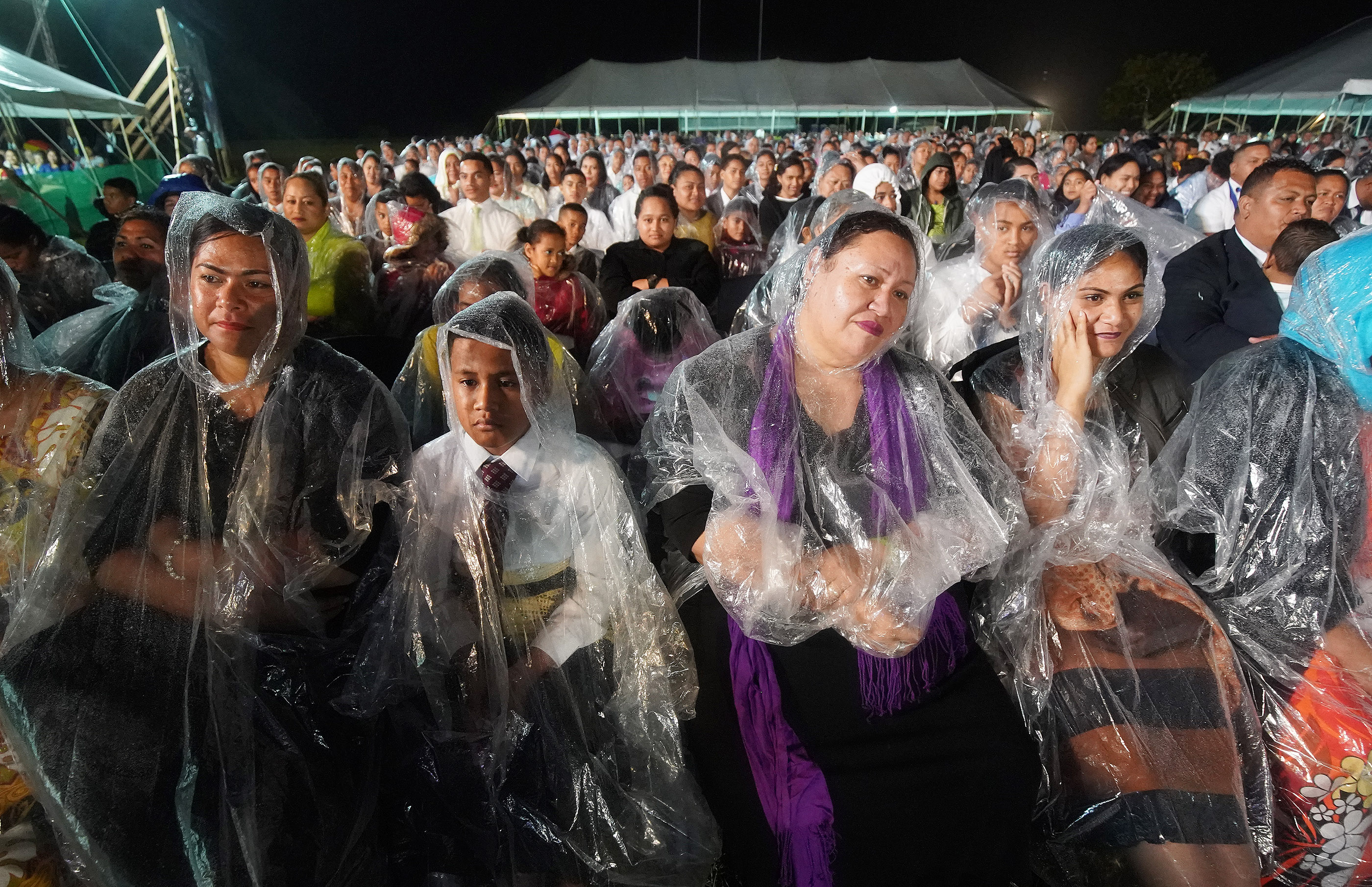 Attendees sit in the rain during a devotional in Nuku'alofa, Tonga, on May 23, 2019.