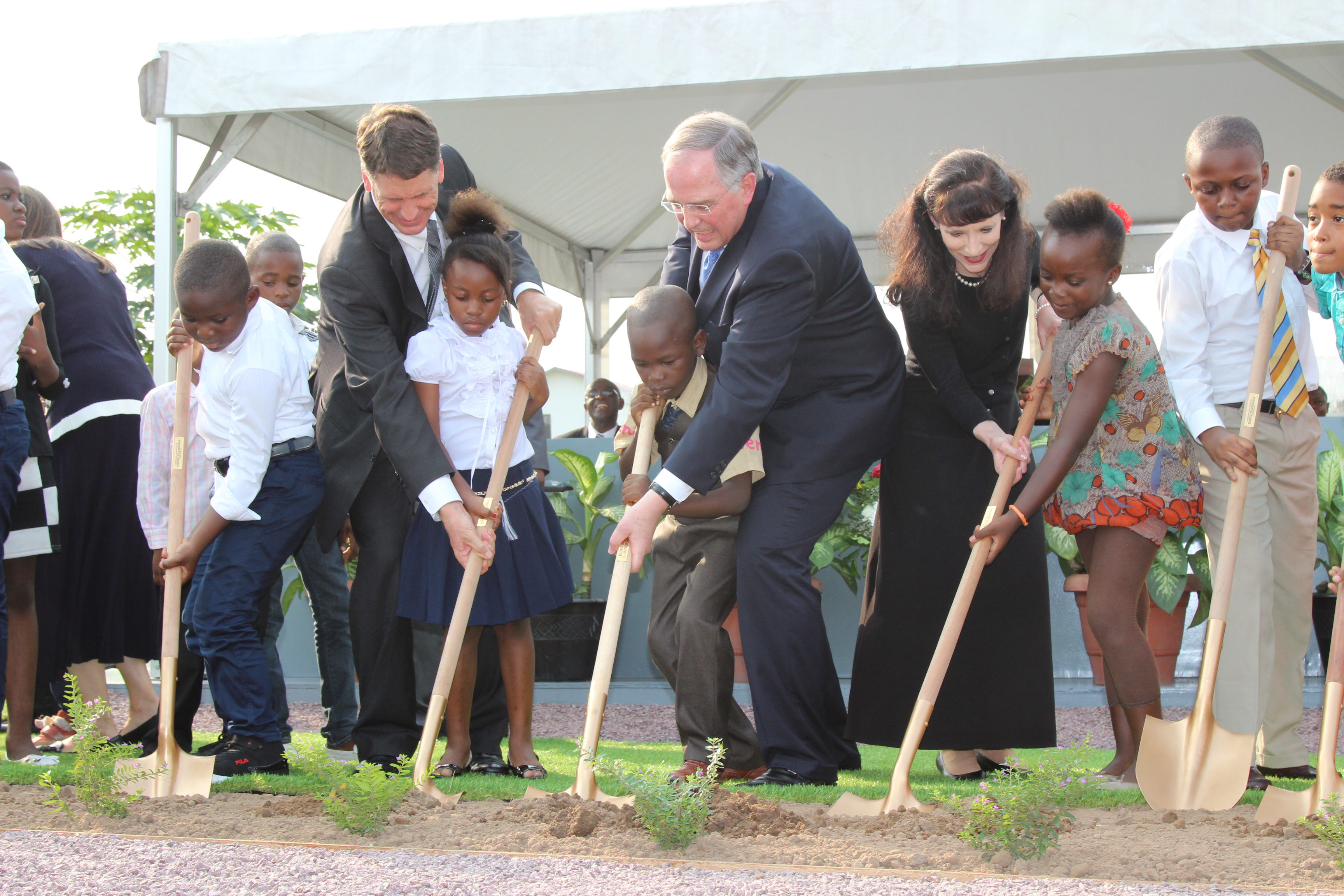 Elder Neil L. Andersen and his wife, Sister Kathy Andersen, and Africa Southeast Area president, Elder Carl B. Cook, help local children as they break ground for the Kinshasa Democratic Republic of the Congo Temple on Friday, February 12, 2016.