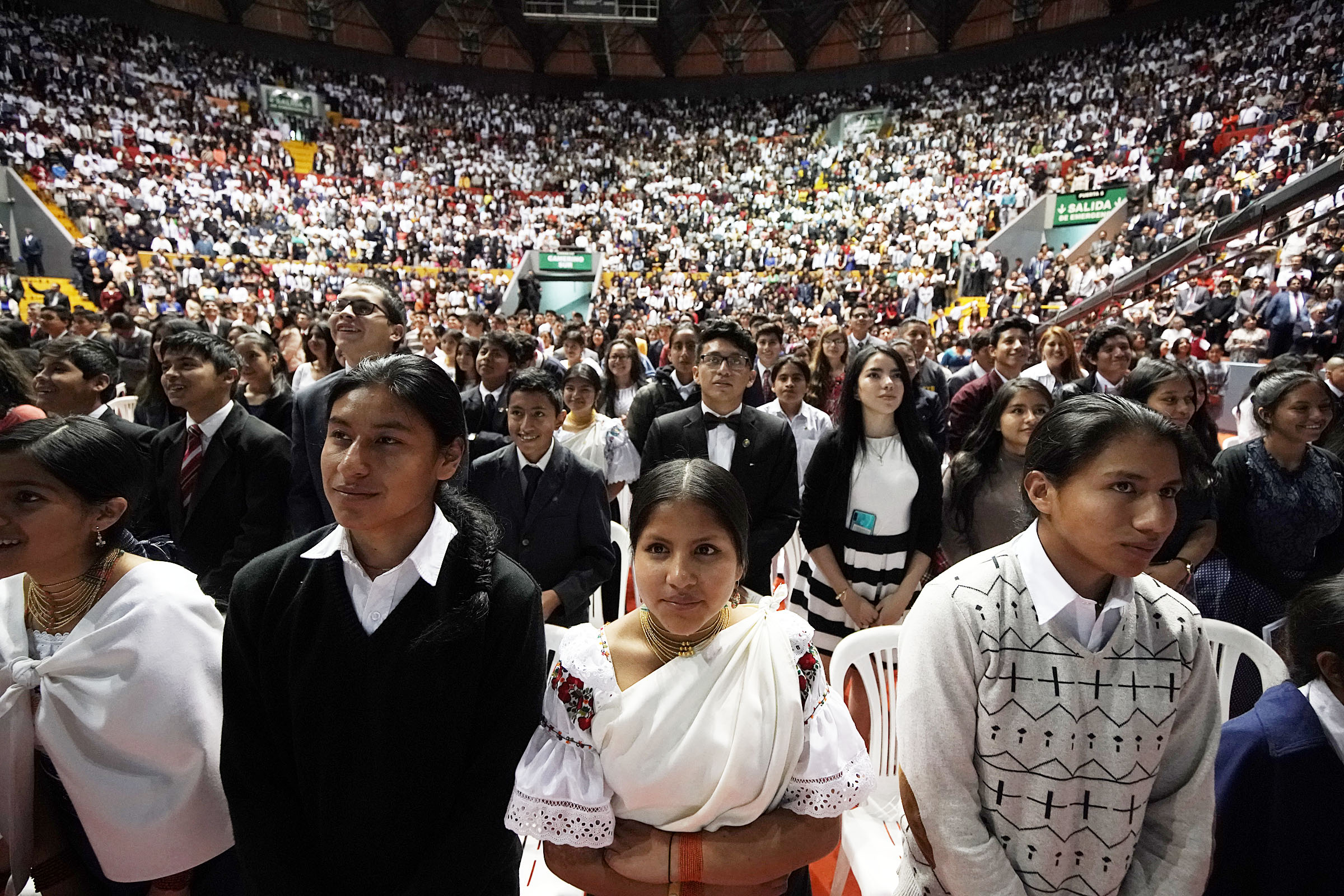 Youth in the audience stand to stretch at the request of President Russell M. Nelson of The Church of Jesus Christ of Latter-day Saints during a Latin America Ministry Tour devotional in Quito, Ecuador, on Monday, Aug. 26, 2019. At center is Nahomi Campo.