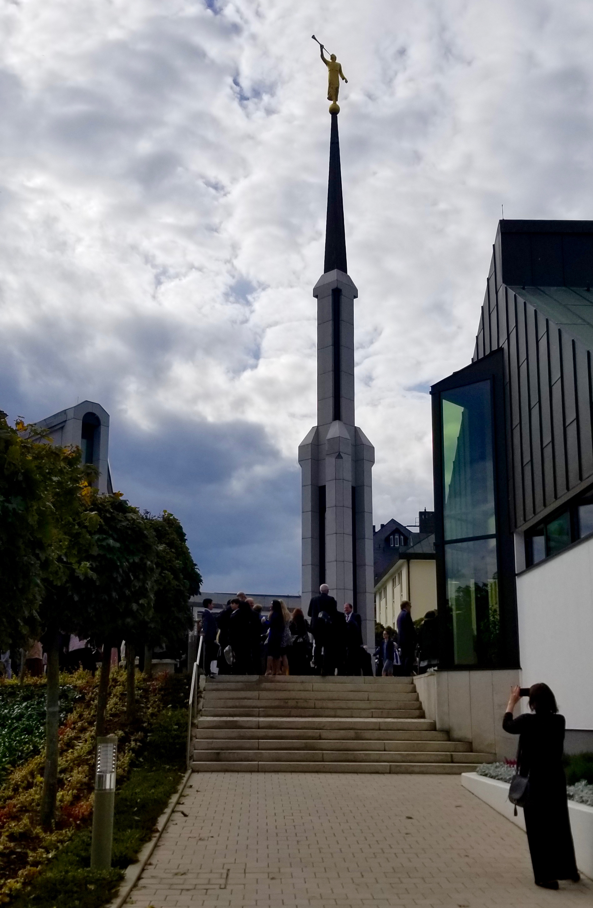A woman takes a photo of the spire between the Frankfurt Germany Temple and the temple annex prior to a rededication session on Sunday, Oct. 20, 2019.