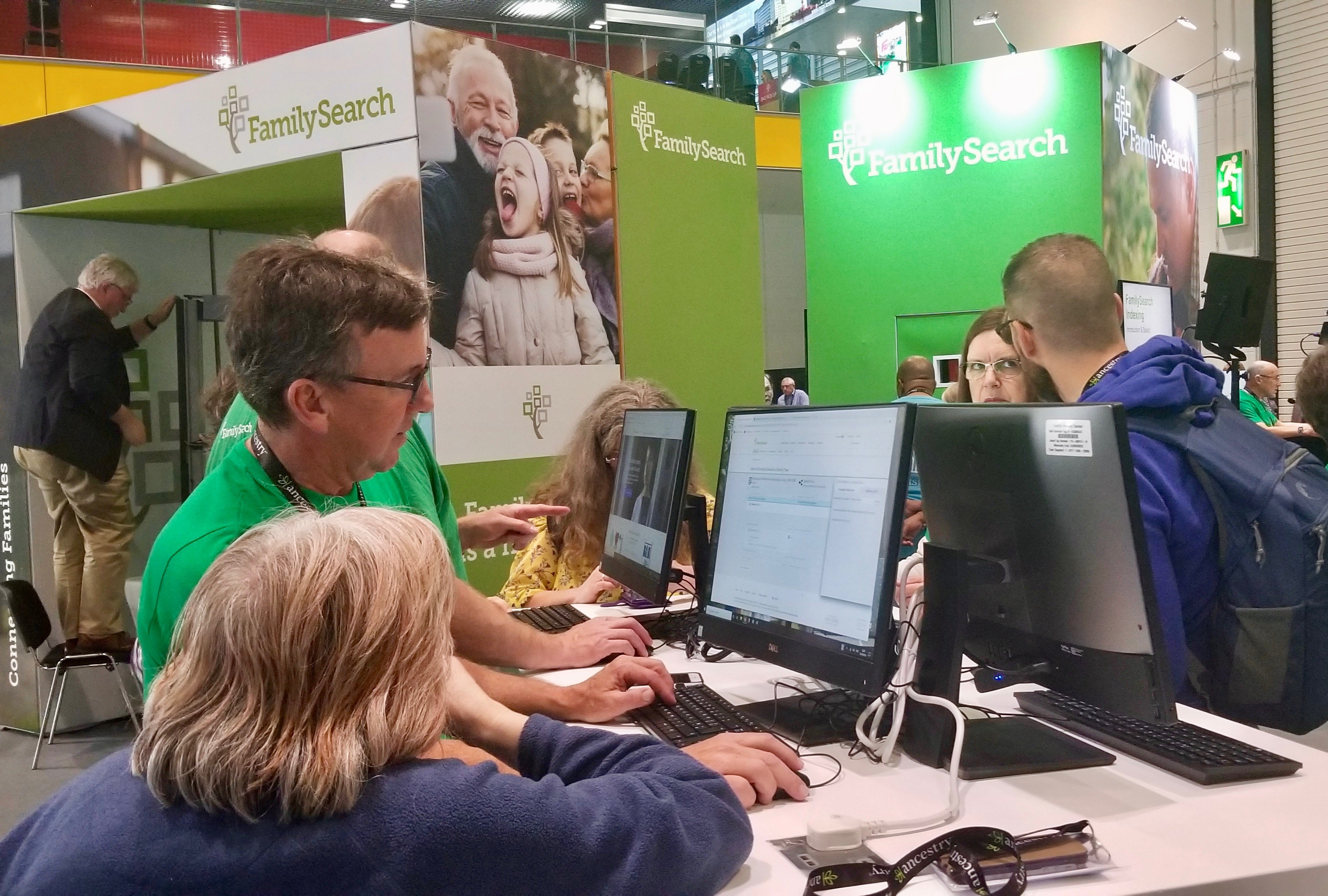 Attendees confer with staff at the FamilySearch booth in the RootsTech London exhibition area at London ExCel convention center on Thursday, Oct. 24, 2019.
