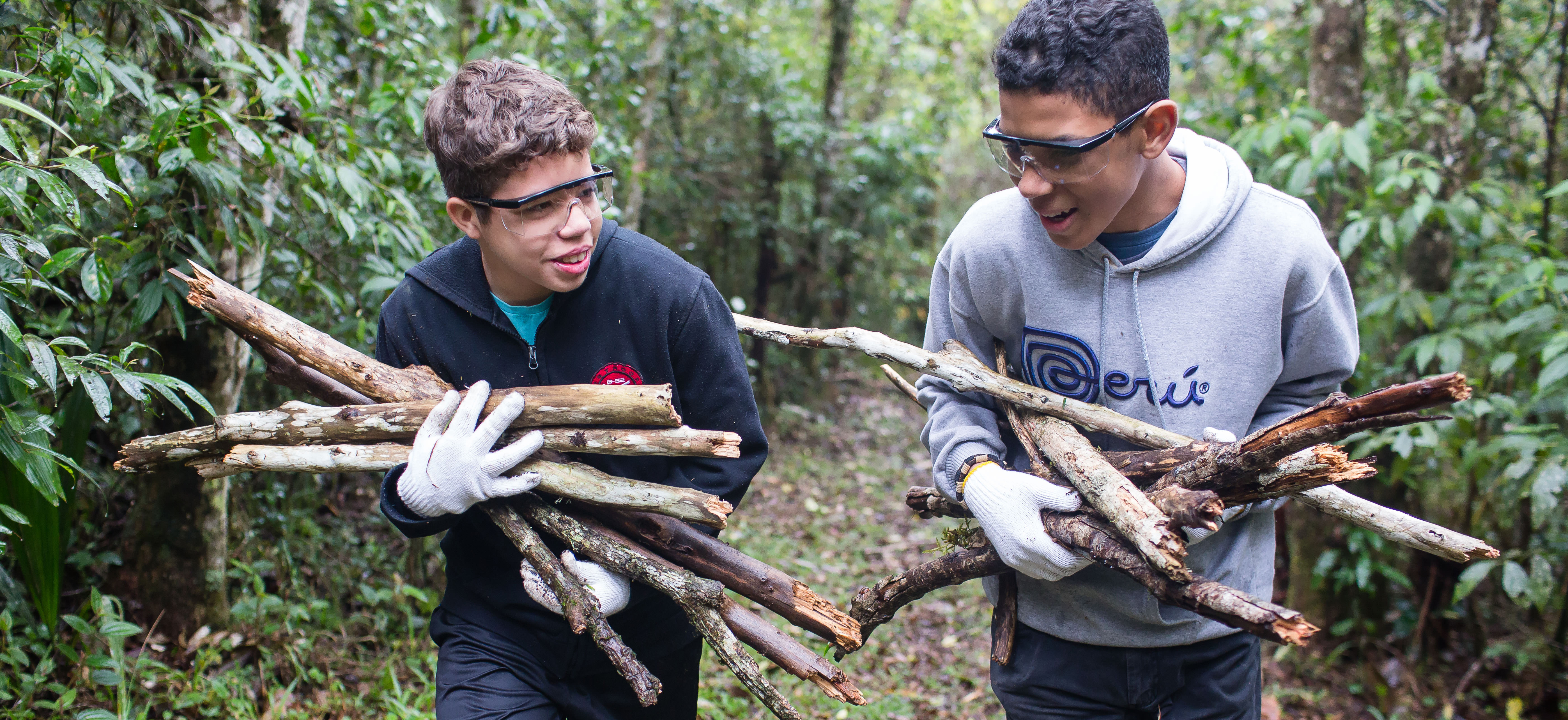 Young men carry sticks during a camping trip. A new camp guide for Aaronic Priesthood quorums has been released.