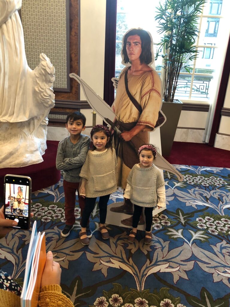 Liam Mecham, 8, Ayla Mecham, 5, and Elsie Mecham, 3, pose for a photo with a life-size cutout of Nephi at a special Book of Mormon Videos screening for Primary children in the Joseph Smith Memorial Building in Salt Lake City on Saturday, Dec. 7, 2019.