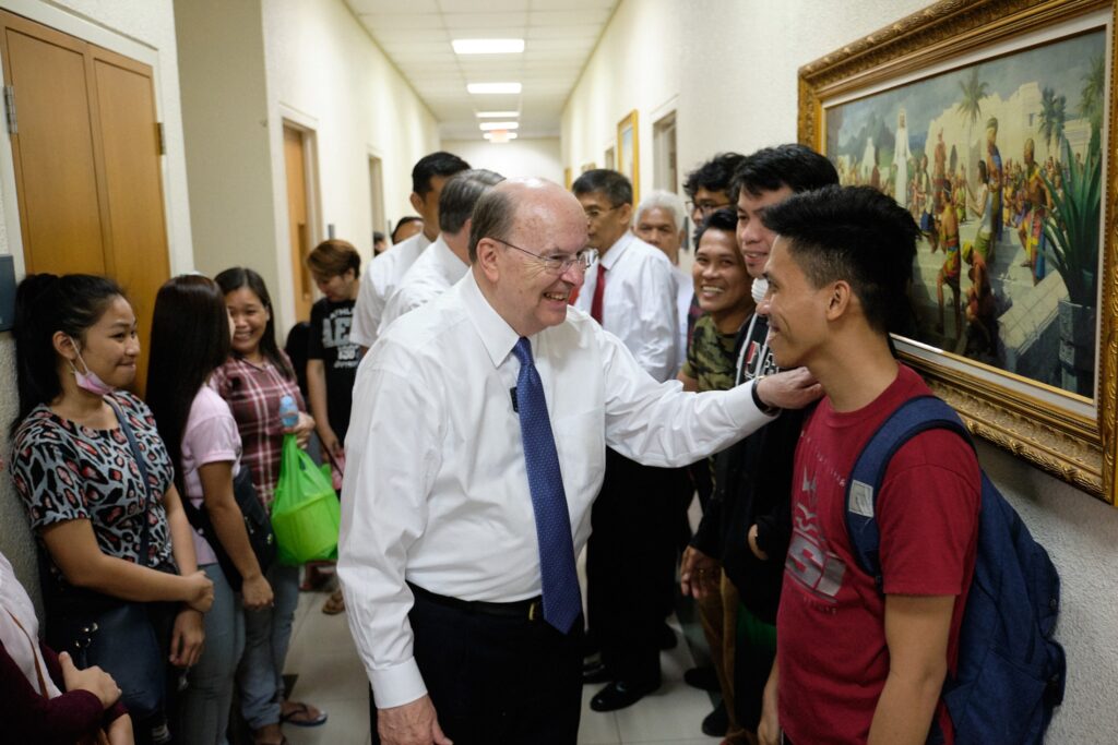 El élder Quentin L. Cook saluda a los Santos de los Últimos Días reunidos en un centro de reuniones local el 15 de enero de 2020, mientras el volcán Taal continúa arrojando cenizas al sur de Manila, Filipinas.