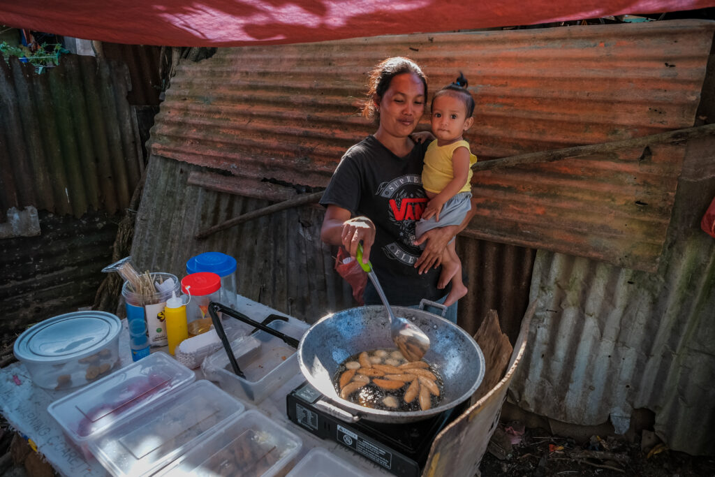 A mother cooks food outside her home in Catarman, Philippines, on Feb. 3, 2020, during a visit from Sister Jean B. Bingham.