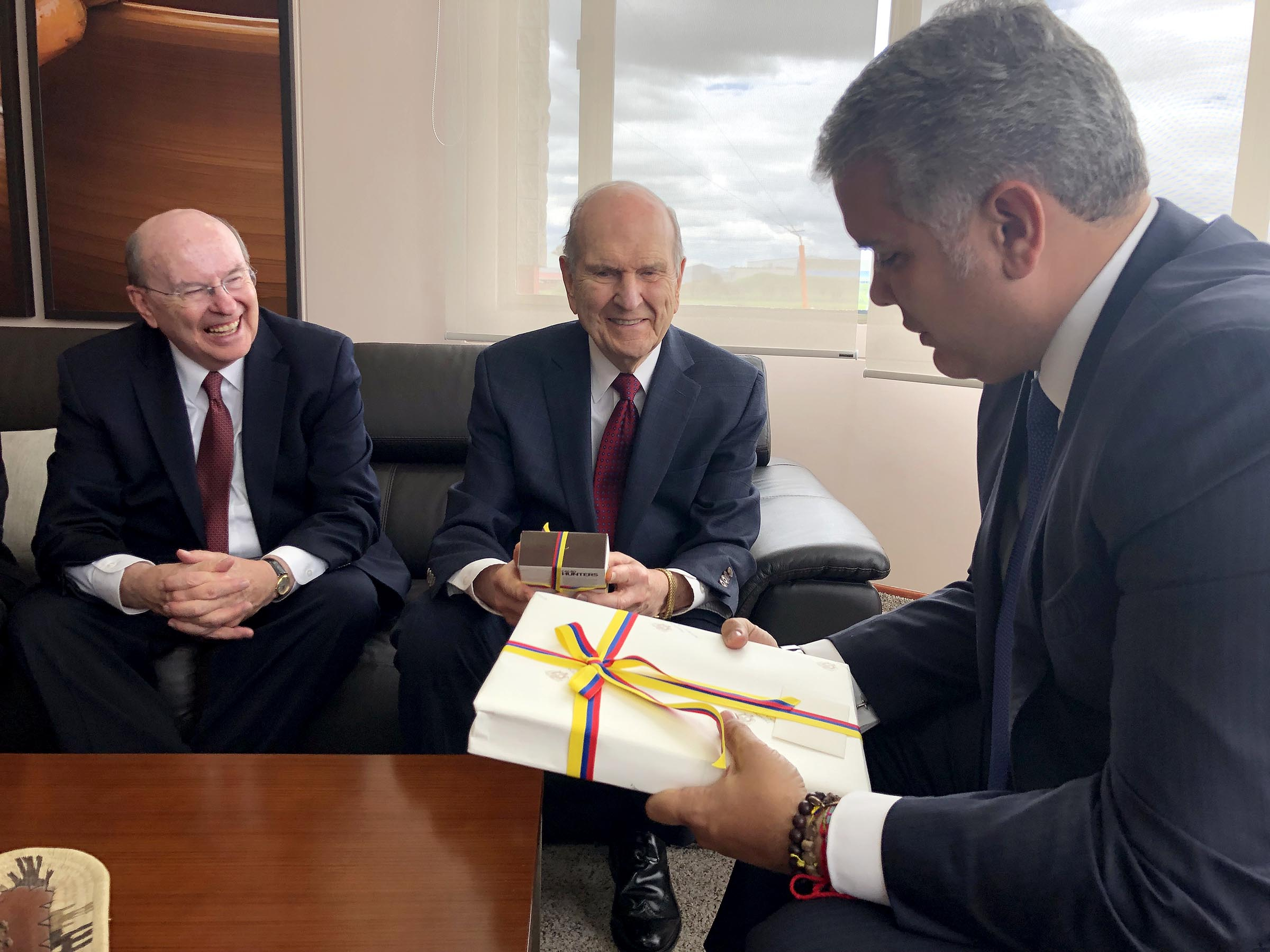 O presidente Russell M. Nelson, de A Igreja de Jesus Cristo dos Santos dos Últimos Dias, ao centro, e o élder Quentin L. Cook, do Quórum dos Doze Apóstolos, à esquerda, presenteiam o presidente da Colômbia, Iván Duque Márquez, à direita, durante o encontro em Bogotá, Colômbia, na segunda-feira, 26 de agosto de 2019.