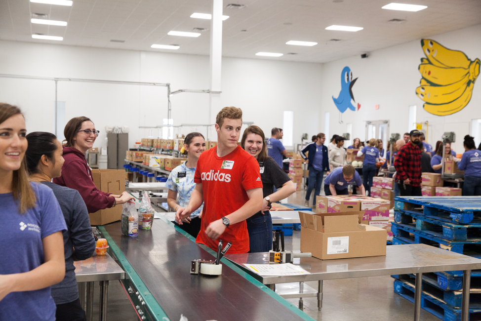 Missionários voluntários no Central Texas Food Bank ficam animados com a visita surpresa do élder Ulisses Soares em 18 de outubro de 2019.