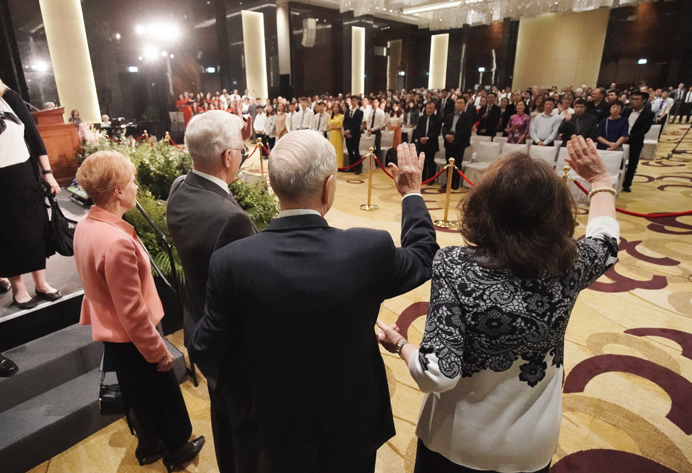 Presidente Russell M. Nelson, de A Igreja de Jesus Cristo dos Santos dos Últimos Dias, e sua esposa, irmã Wendy Nelson, e élder D. Todd Christofferson, do Quórum dos Doze Apóstolos de A Igreja de Jesus Cristo dos Santos dos Últimos Dias, e sua esposa, irmã Kathy Christofferson, acenam para congregação após um devocional em Hanói, Vietnã, no domingo, dia 17 de novembro, 2019.