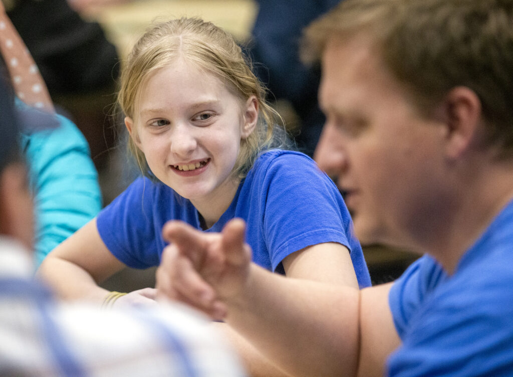 Gwen Buehner sonríe mientras Dave Hansen, un especialista del cuórum de presbíteros, habla en una reunión de juegos para jóvenes y líderes del Barrio Willow Creek 6o, Estaca Sandy Utah Willow Creek de La Iglesia de Jesucristo de los Santos de los Últimos Días, el miércoles, 22 de enero de 2020.